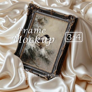 May include: A black ornate picture frame with gold detailing containing an image of a bird on a snowy pine branch. The text Frame Mockup 3:4 and PSD Smart Object are visible on the frame. The frame is set against a draped cream satin fabric.