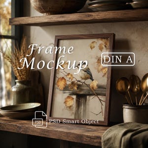 Pode incluir: Uma moldura de madeira escura contendo uma ilustração de um pequeno pássaro pousado num galho com folhas de outono douradas. A moldura apresenta o texto Frame Mockup e DIN A, com um ícone PSD Smart Object no canto inferior esquerdo.