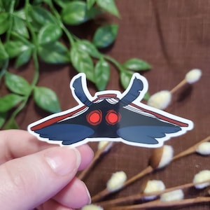 May include: A sticker of a black and red moth with large, red eyes. The moth has a wingspan of about 5 inches.
