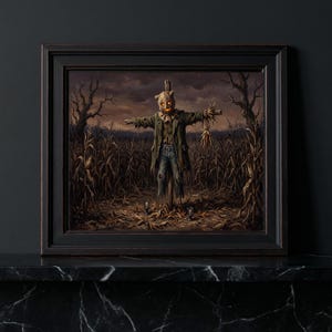 May include: A framed wall art print depicting a scarecrow with a burlap sack head and glowing orange eyes, wearing a green coat and blue jeans, standing in a dark, withered cornfield under a cloudy sky, enclosed in a dark wooden frame.