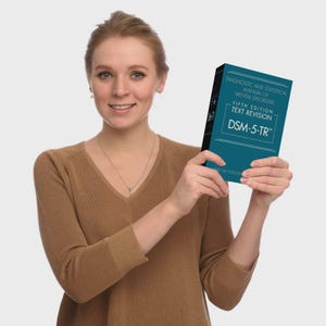 May include: A teal-colored book titled Diagnostic and Statistical Manual of Mental Disorders, Fifth Edition, Text Revision, DSM-5-TR. The cover features white text on a dark teal background, with the American Psychiatric Association name at the bottom.