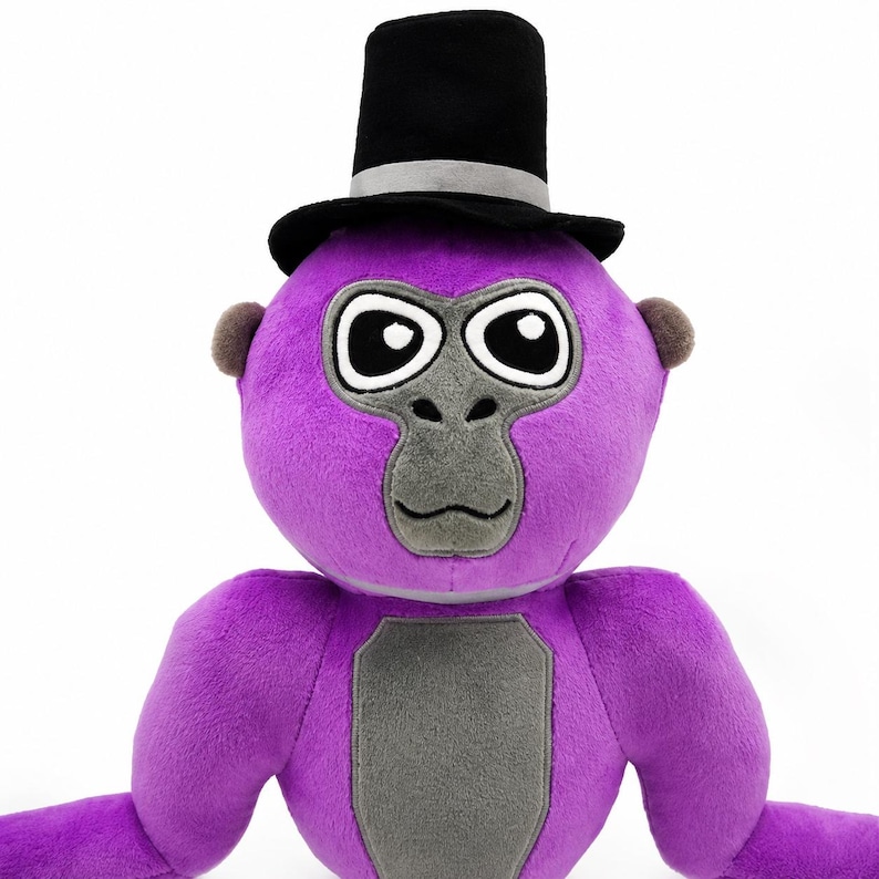 May include: A plush gorilla toy featuring bright purple fur, a gray face, and a gray chest patch. The gorilla has large black and white eyes and is wearing a black top hat with a silver band. The toy has small brown ears and long arms.