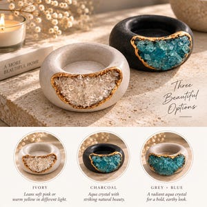 May include: Two round candle holders with a central circular opening. One holder is ivory with clear crystals, and the other is charcoal with blue crystals. Both feature gold-trimmed edges. Text reads: A MORE BEAUTIFUL HOME, Three Beautiful Options.