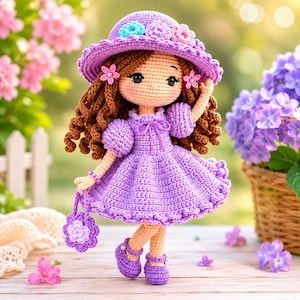 May include: A handmade crochet doll in a purple dress and matching hat, adorned with floral accents. The doll has brown curly hair and is holding a small purse. The doll is wearing purple shoes. The doll is approximately 10 inches tall.
