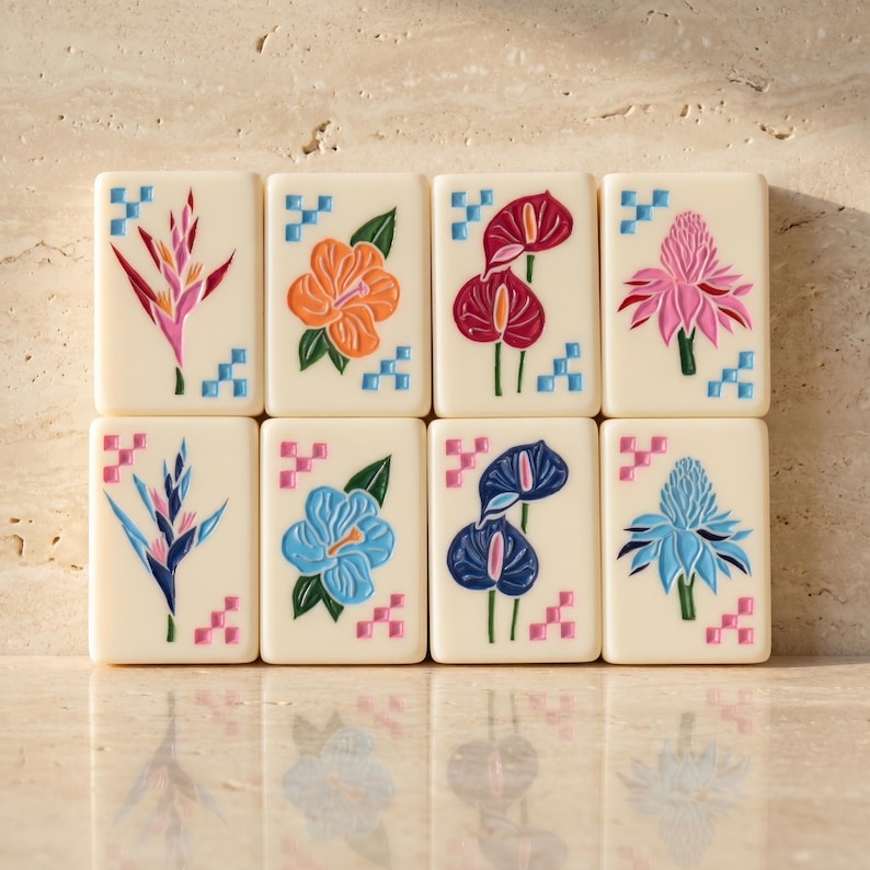 May include: Eight rectangular off-white tiles arranged in two rows, each featuring a colorful engraved tropical flower illustration and small blue or pink geometric corner accents. The designs include bird of paradise, hibiscus, and anthurium flowers.