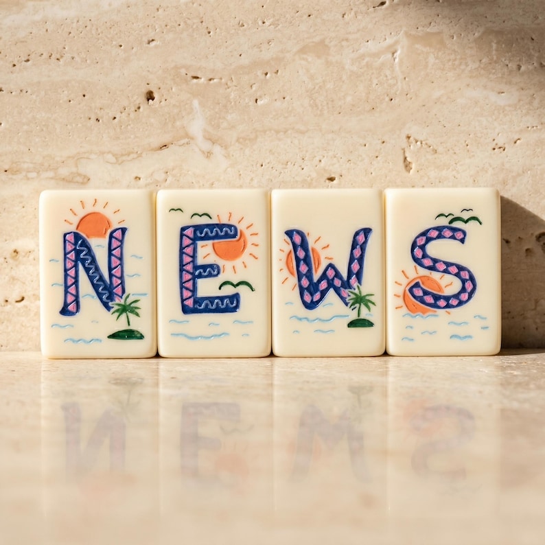May include: Four off-white rectangular tiles arranged in a row, each featuring a hand-painted letter spelling NEWS. The letters are dark blue with pink accents, surrounded by orange suns, green palm trees, and blue wavy water illustrations.