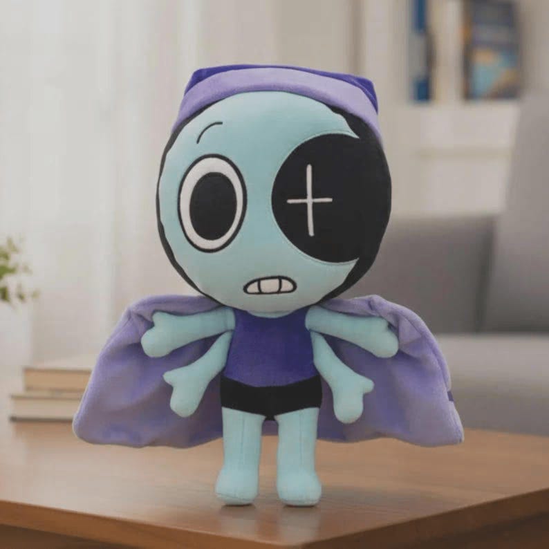 Peut inclure: Une poup&eacute;e en peluche avec un visage bleu clair, un grand cache-&oelig;il noir et une cape violette. La poup&eacute;e a un chapeau violet, une petite bouche et une croix sur le cache-&oelig;il. Elle porte une chemise violette et un short noir. La poup&eacute;e est debout.