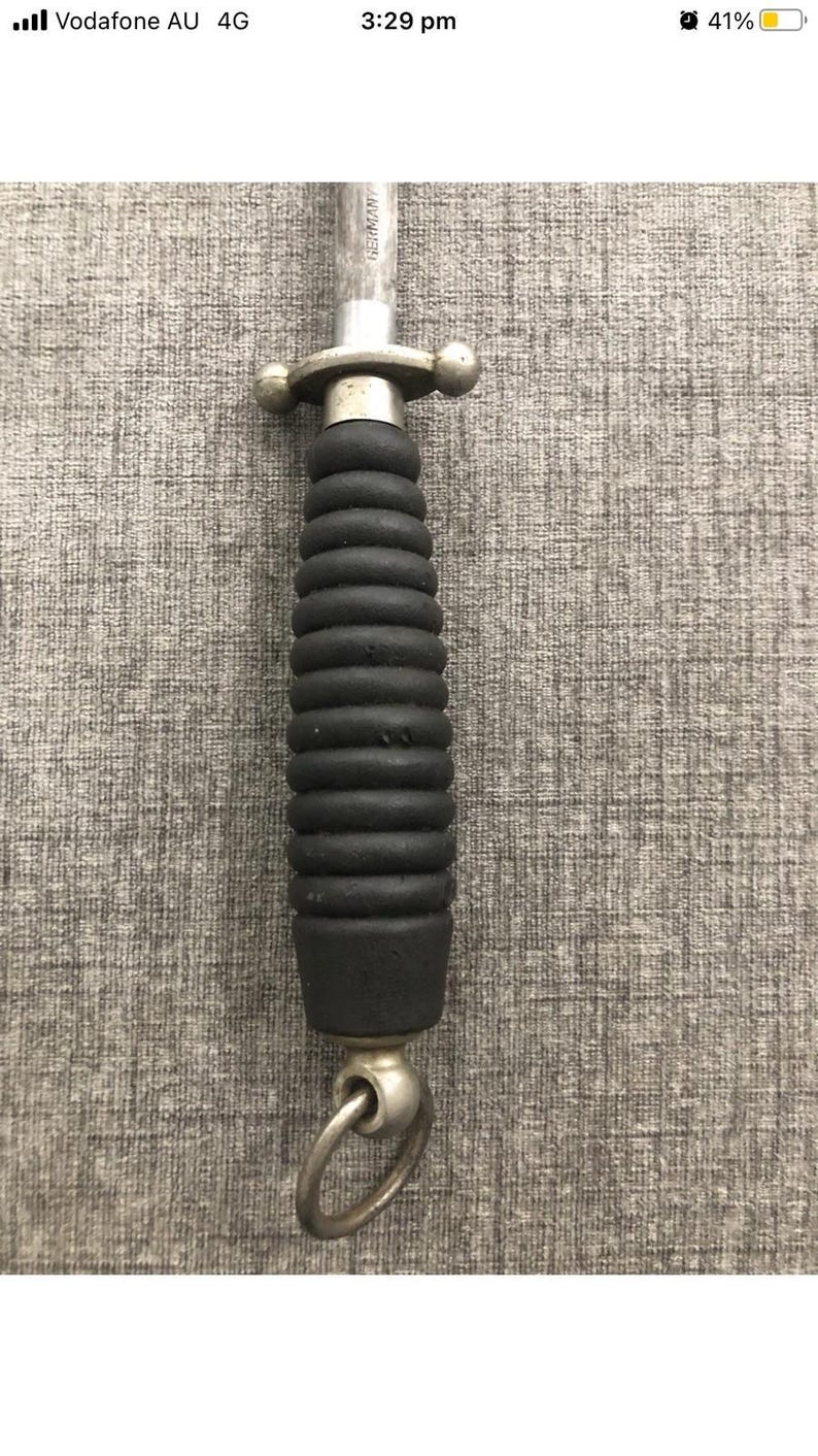 May include: A knife sharpener with a black, ridged handle and a silver metal guard and ring. The blade is visible and marked "GERMANY". The handle is approximately 4 inches long.