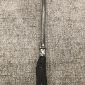 May include: A vintage steel knife sharpener with a dark brown, textured handle. The handle is made of a material that resembles wood or antler. The metal sharpening rod is long and cylindrical, with a decorative silver band near the handle.