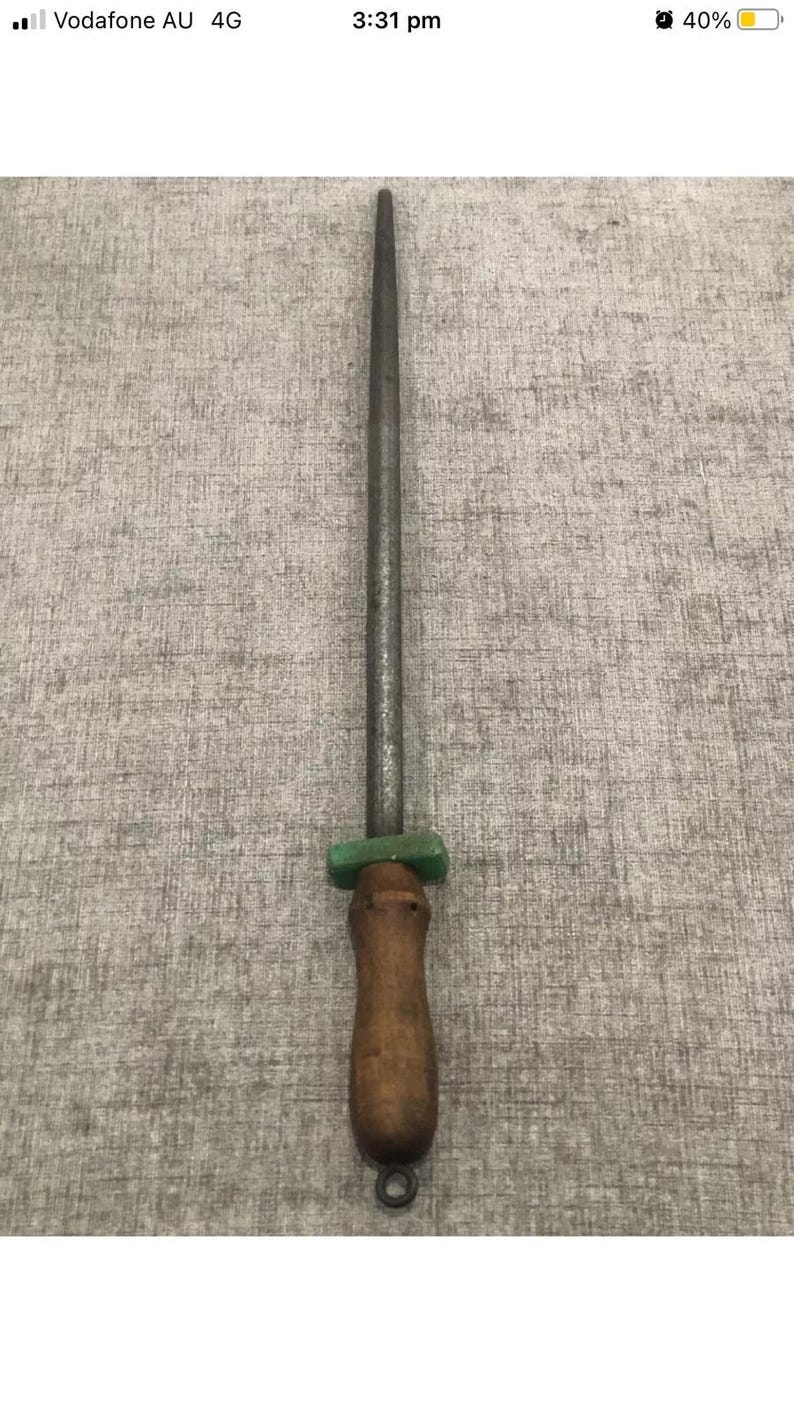 May include: A knife sharpening steel with a wooden handle and a green bolster. The steel is long and cylindrical, designed for honing the edge of knives. The handle has a loop for hanging.