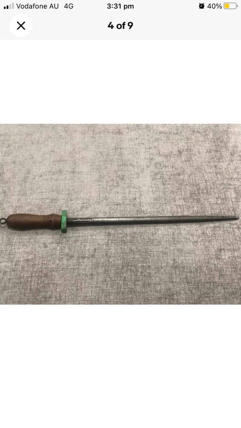 May include: A knife sharpening steel with a dark wooden handle, a green ring, and a steel rod. The sharpening steel is used to maintain the sharpness of knives. The handle has a small loop for hanging.