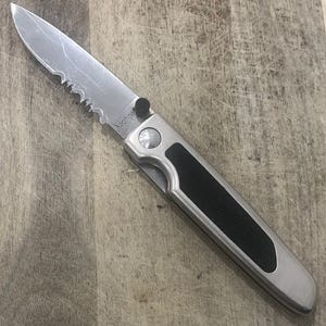 Pode incluir: Uma faca dobr&aacute;vel prateada com uma l&acirc;mina parcialmente serrilhada e uma pega preta. A faca est&aacute; sobre uma superf&iacute;cie de madeira. A marca "Kershaw" &eacute; vis&iacute;vel na l&acirc;mina.