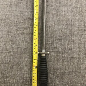 May include: A steel knife sharpener with a black handle and a ring at the end. The sharpener is approximately 16 inches long. A yellow measuring tape is placed next to the sharpener.