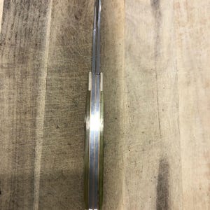Op de afbeelding: Een close-up van een zakmes met een zilveren lemmet en een lichtgroen handvat. Het mes is gesloten, met het lemmet in het handvat. Het handvat heeft een messingkleurige accent.
