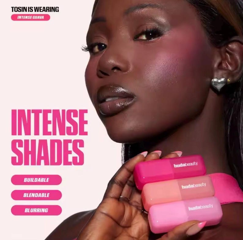 May include: A woman with dark skin is shown wearing Intense Guava makeup. She holds three pink Huda Beauty lip products. The image features the text "Intense Shades," with descriptors "Buildable," "Blendable," and "Blurring."