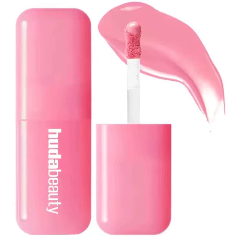 May include: A pink lip product with the text "hudabeauty" on the tube. The product is shown with the applicator brush and a swatch of the lip color. The lip product is a bright, bubblegum pink color.