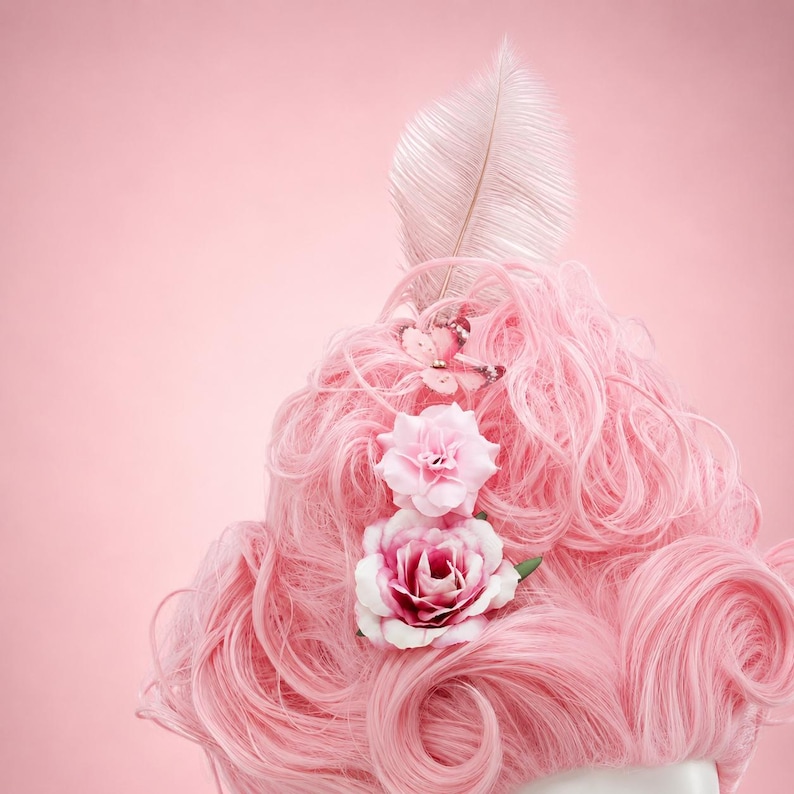 May include: A pink wig with large curls, decorated with a large feather and two pink fabric roses. A small butterfly decoration is also attached. The wig is set against a soft pink background, creating a whimsical and elegant aesthetic.