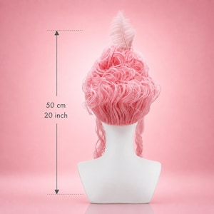 May include: A pink wig with voluminous curls and a feather accent, displayed on a white mannequin head. The wig is approximately 50 cm (20 inches) in length, with long, flowing strands. The background is a solid pink.