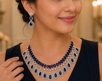Peut inclure: Une parure de bijoux composée d'un collier et de boucles d'oreilles pendantes assorties. Le collier présente une série de pierres bleues en forme de poire entourées de petites pierres blanches, disposées en gradins. Les boucles sont assorties.