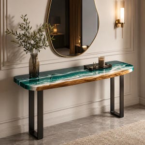 Puede incluir: Una mesa consola larga con un tablero de madera natural de borde vivo y una incrustación de resina brillante que imita la apariencia de las olas del océano en tonos verde azulado profundo, verde y blanco. La mesa tiene dos patas de metal negro.