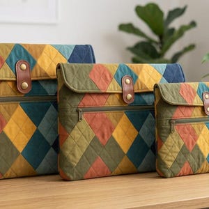 Könnte beinhalten: Drei gesteppte Taschen in absteigender Größe, jede mit einem mehrfarbigen Rautenmuster in Olivgrün, Rostorange, Senfgelb und Marineblau. Jede Tasche verfügt über einen Frontreißverschluss, einen Klappenverschluss mit brauner Kunstlederlasche und goldfarbene Beschläge.