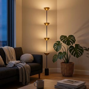 May include: A contemporary floor lamp featuring four brass-toned, bowl-shaped shades. The lamp has a black pole and a marble base. It is positioned in a living room, beside a sofa and a potted plant.