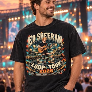 May include: A black short-sleeve t-shirt featuring a graphic of Ed Sheeran playing an acoustic guitar on stage. The text reads Ed Sheeran Loop Tour 2026 with city names listed below. The design includes colorful light trails and concert imagery.