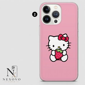 May include: Pink phone case featuring a Hello Kitty graphic holding a strawberry. The case has a clear border and a glossy finish. The phone case is designed for a smartphone with multiple camera lenses.
