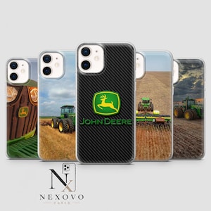 May include: A collection of five phone cases featuring John Deere designs. The central case has a black carbon fiber texture with the John Deere logo in green and yellow. Other cases display images of John Deere tractors in fields.