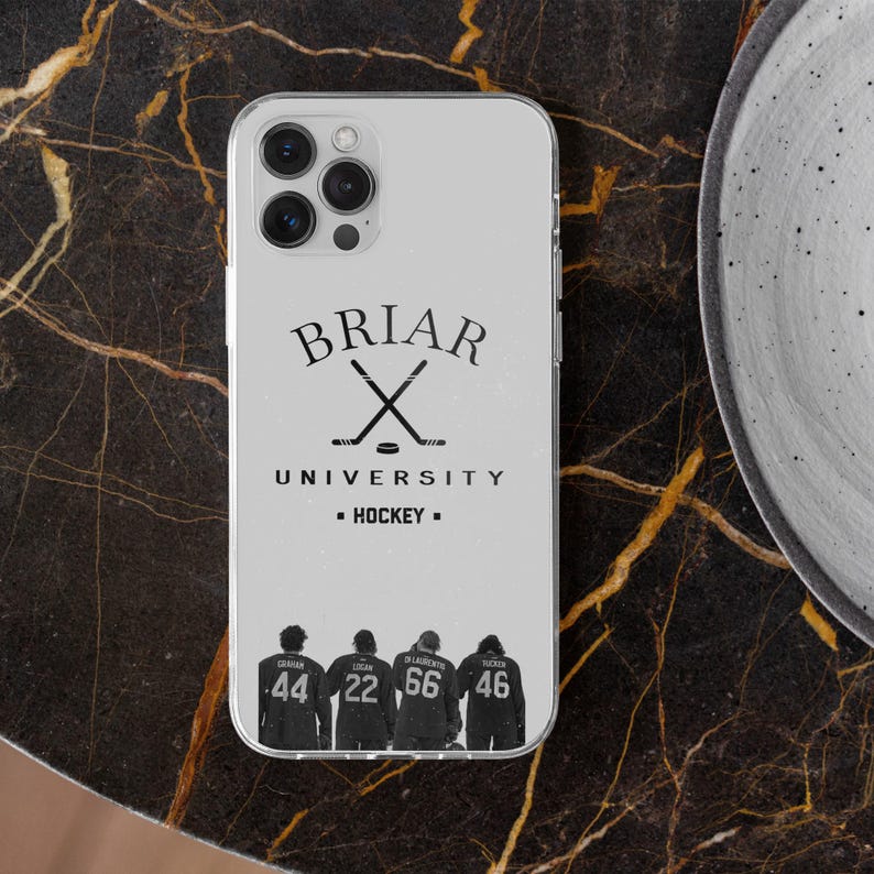 May include: A clear phone case featuring the text "BRIAR UNIVERSITY - HOCKEY" with crossed hockey sticks. Below, four figures are shown with jersey numbers 44, 22, 66, and 46. The case is on a dark, patterned surface.