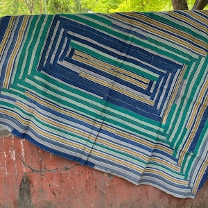 Puede incluir: Un textil rectangular que presenta un patrón concéntrico de rayas en tonos azul marino, verde azulado, verde y crema. La tela muestra un diseño estructurado y superpuesto con bandas de colores alternas que crean un efecto de marco geométrico.