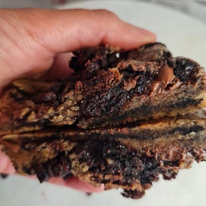 Peut inclure: Gros plan sur un cookie au chocolat coupé en deux, révélant un intérieur riche et sombre. Le cookie a un extérieur légèrement croustillant et un centre moelleux avec des pépites de chocolat visibles. Le cookie est tenu dans une main.