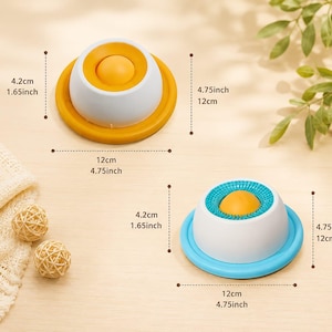 Puede incluir: Dos juguetes sensoriales en forma de c&uacute;pula con una bola amarilla central. Uno tiene base amarilla y parte superior lisa, el otro base azul y anillo azul texturizado. Ambos miden 12 cm de di&aacute;metro y 4,2 cm de altura, seg&uacute;n las etiquetas.