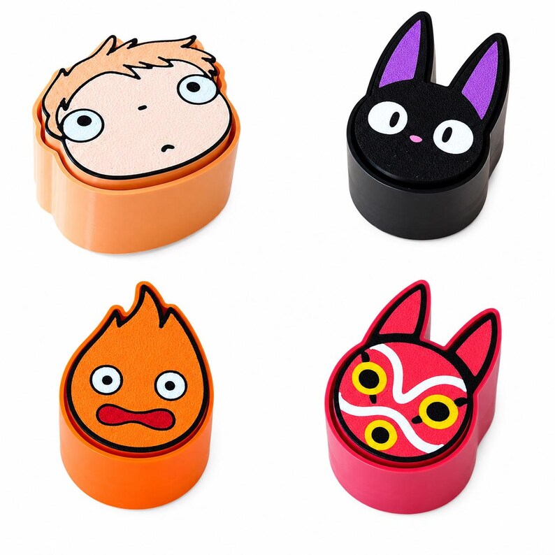 May include: A set of four circular stamps featuring character designs: a light-skinned face with wide eyes, a black cat with purple ears, an orange flame with a surprised expression, and a red mask with yellow eyes and white swirling patterns.
