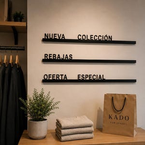 Può includere: Interno di un negozio di abbigliamento con maglioni piegati, una borsa della spesa e una pianta in vaso. La parete presenta scritte nere che recitano "NUOVA COLLEZIONE", "SALDI" e "OFFERTA SPECIALE". Abiti appesi.