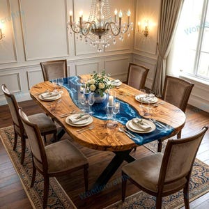 May include: An oval wooden dining table with a blue resin river design, set for a meal. The table is surrounded by six upholstered chairs. A chandelier hangs above, illuminating the dining area.