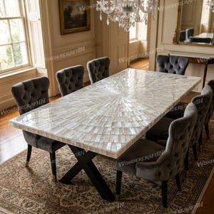 Pode incluir: Uma mesa de jantar retangular com incrustação de madrepérola branca iridescente disposta num padrão de raios de sol no tampo, suportada por uma base de metal preto em forma de X, rodeada por seis cadeiras de jantar cinzentas estofadas.