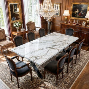 Pode incluir: Uma mesa de jantar retangular com tampo de mármore branco com veios cinzentos e base de metal preto, rodeada por oito cadeiras estofadas escuras com estruturas de madeira, sobre um grande tapete estampado numa sala de jantar formal.