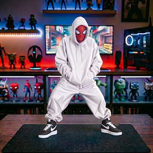 Op de afbeelding: Een Spider-Man actiefiguur met een effen witte hoodie en een bijpassende witte joggingbroek. Het figuur heeft een rood masker met witte ooglenzen en draagt zwart-witte hoge sneakers met een wit swoosh-logo aan de zijkanten.