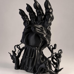 Puede incluir: Una escultura impresa en 3D de color negro mate que muestra una mano grande con garras extendida hacia arriba, con nudillos prominentes y garras afiladas. La base está rodeada de estructuras complejas similares a raíces. El texto GEEK & GAMING STUDIO es visible.