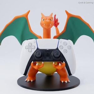 May include: An orange and green Charizard figure standing on a black circular base, holding a white and black PlayStation 5 game controller. The figure features orange skin, teal-colored wings, and a flame on its tail. Text reads Geek & Gaming Studio.