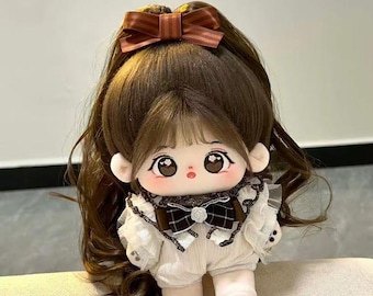 May include: A plush doll with long brown hair, a brown bow, and a white outfit with a black bow tie. The doll has large, expressive eyes and a paw print on its foot. The doll is a cute and cuddly toy.