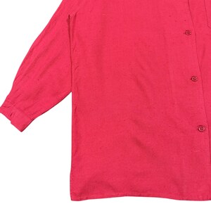 Puede incluir: Una camisa roja brillante de manga larga con botones en la parte delantera y un bolsillo en el pecho. La camisa tiene un aspecto texturizado y un cuello cl&aacute;sico. La manga est&aacute; abotonada en el pu&ntilde;o.