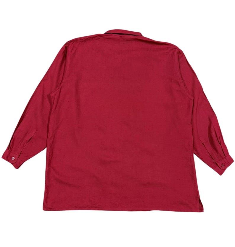 Puede incluir: Una camisa de manga larga con botones en un tono rojo intenso liso. La camisa presenta un cuello cl&aacute;sico y pu&ntilde;os abotonados. La tela parece ser un material ligero, adecuado para climas c&aacute;lidos.