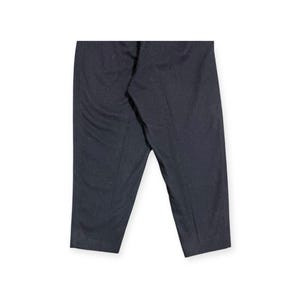 Puede incluir: Un pantal&oacute;n de color gris carb&oacute;n oscuro que presenta una textura sutilmente moteada en toda la tela. El pantal&oacute;n tiene un corte recto con una raya central visible que recorre la parte delantera de cada pierna, dando un aspecto estructurado.