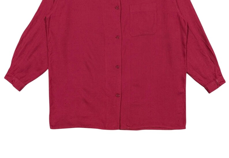 Puede incluir: Camisa de manga larga en un tono rojo intenso. Presenta una botonadura frontal, un bolsillo en el pecho y un cuello cl&aacute;sico. La tela parece ser un material suave y tejido. Las mangas terminan en pu&ntilde;os abotonados.