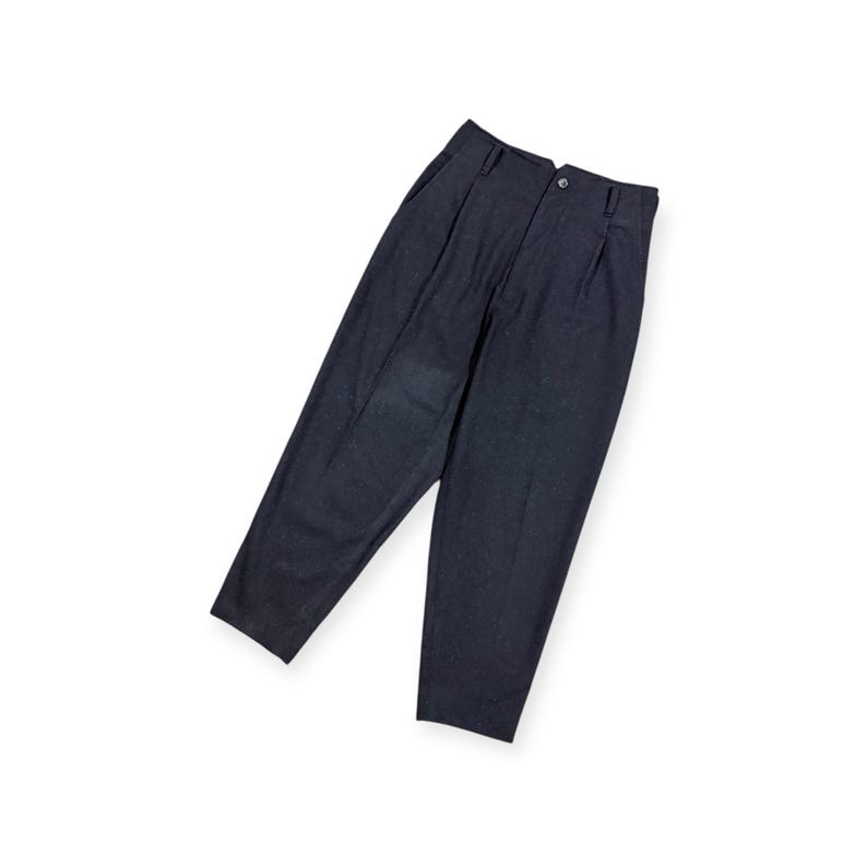Puede incluir: Un pantal&oacute;n de color gris carb&oacute;n oscuro con dise&ntilde;o de cintura alta, pliegues frontales, cierre de bot&oacute;n, cremallera y trabillas para cintur&oacute;n. La prenda presenta una silueta de pierna c&oacute;nica y un acabado de tela texturizada.
