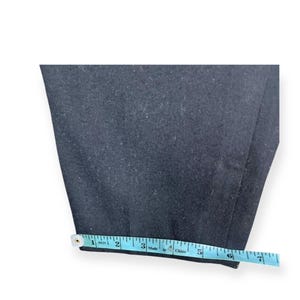 Puede incluir: Un pantal&oacute;n de color azul marino oscuro con un dobladillo recto. Una cinta m&eacute;trica de color azul claro est&aacute; colocada a lo largo del borde inferior de la tela, indicando una anchura de aproximadamente 16,5 cm en la abertura de la pierna.