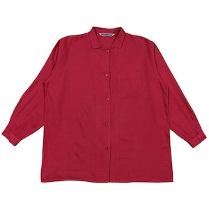 Puede incluir: Una camisa abotonada de manga larga en un tono rojo intenso. La camisa presenta un cuello cl&aacute;sico, un bolsillo en el pecho y botones en la parte delantera. La tela parece ser ligera.