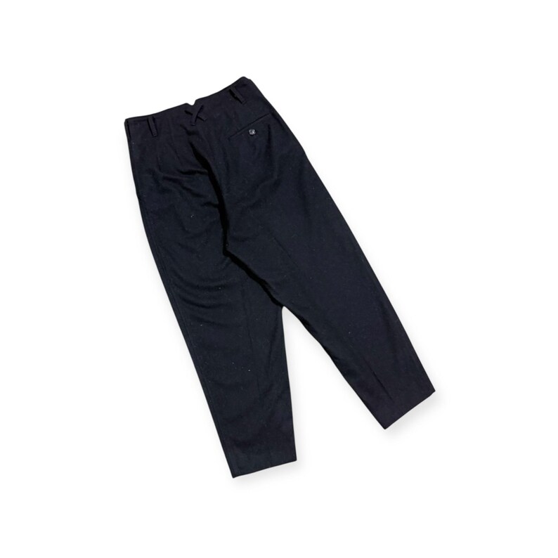 Puede incluir: Un pantal&oacute;n de color azul marino oscuro con dise&ntilde;o de cintura alta, un bolsillo trasero con cierre de bot&oacute;n, trabillas para cintur&oacute;n y un corte estructurado y entallado que se estrecha ligeramente hacia el dobladillo, visto desde atr&aacute;s.